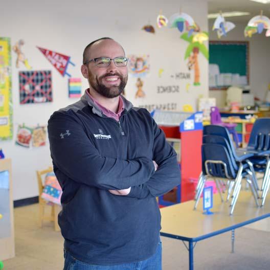 A graduate student standing in a school classroom